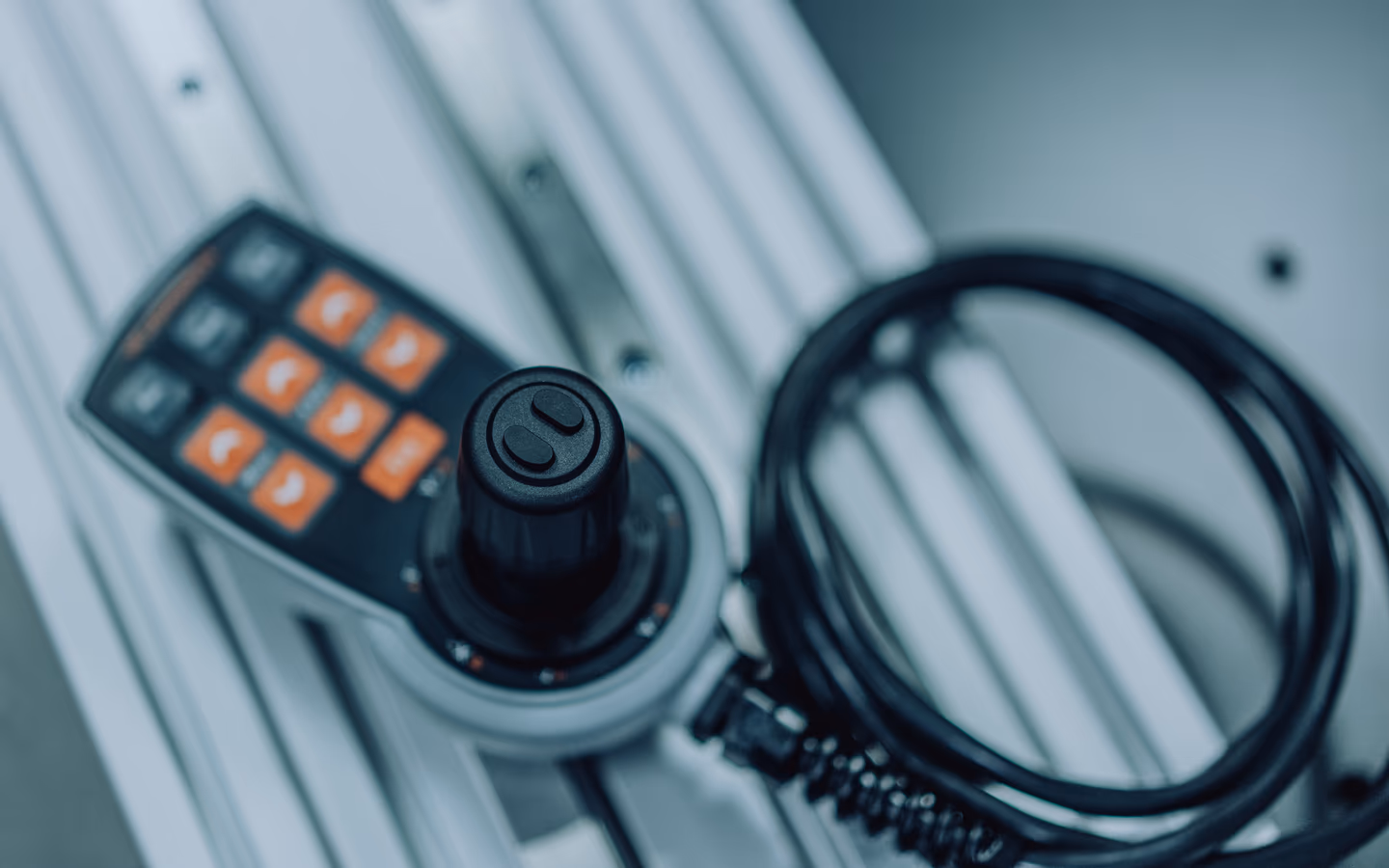 Joystick control unit with orange function keys and coiled cable on an aluminium profile
